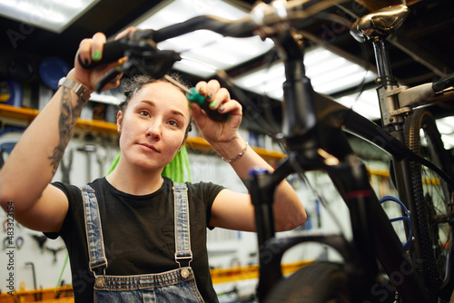 Smiling woman repairing bike in workshop