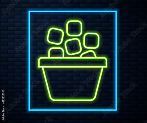 Glowing neon line Ice bucket filled with ice cubes icon isolated on brick wall background. Vector