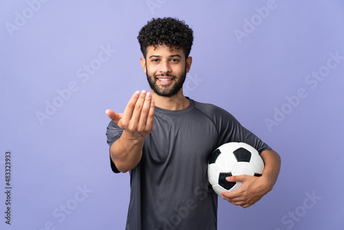 Handsome Moroccan young football player man over isolated on purple background inviting to come with hand. Happy that you came