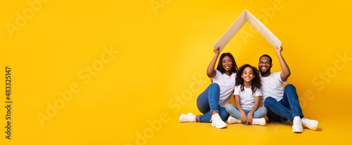 Bild auf Leinwand Happy African American parents holding cardboard roof above daughter, panorama
