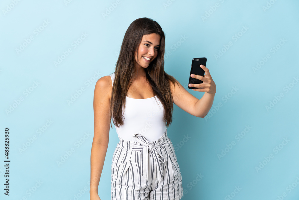 Young brazilian woman isolated on blue background making a selfie Young brazilian woman isolated on blue background making a selfie