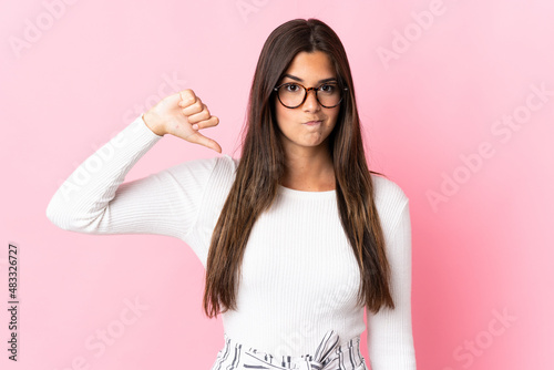 Young brazilian woman isolated on pink background showing thumb down with negative expression © luismolinero