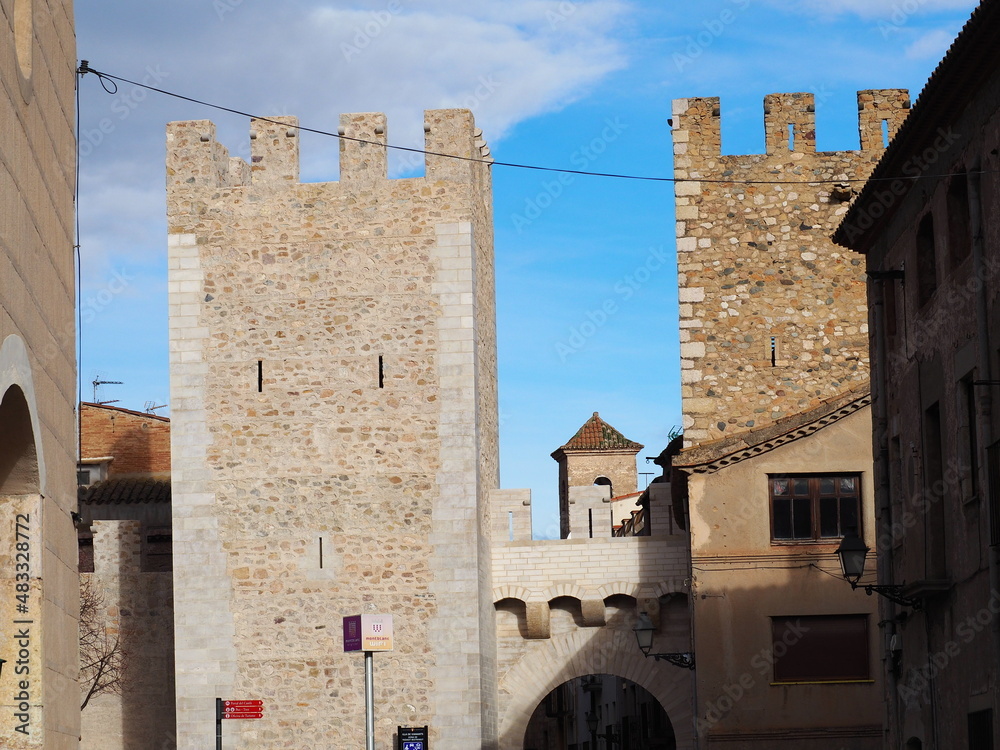 un matacán sobre el portal de castlá custodiado por dos torres castillo en la villa medieval de montblanch, al fondo, el campanario de la iglesia de san miguel, tarragona, españa, europa