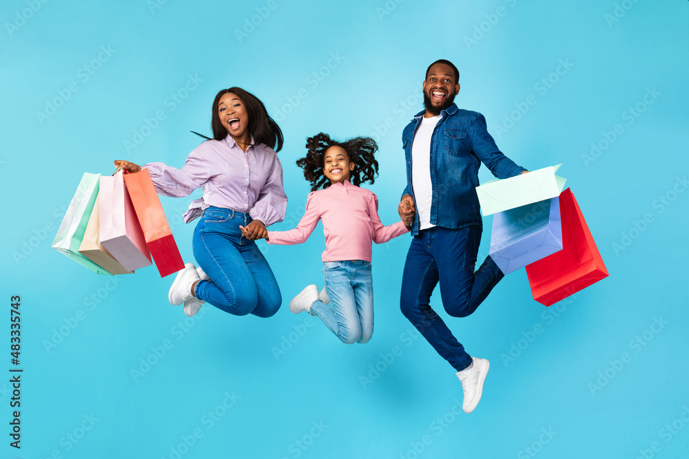 Excited cheerful black people jumping and holding shopping bags