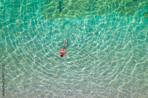 Top  aerial view. Young beautiful woman in a red bikini panties swimming in sea water on the sand beach. Drone  copter photo. Summer vacation. View from above.