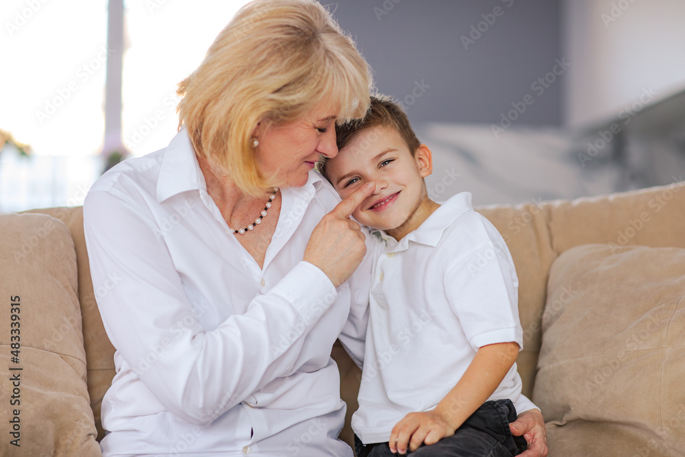 Grandmother posing with a boy sitting in the sofa. High quality photo.