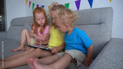 Frustrated redhead girl looking at blond friend playing with tablet computer. Negative emotions. Smooth camera motion shot with gimbal.