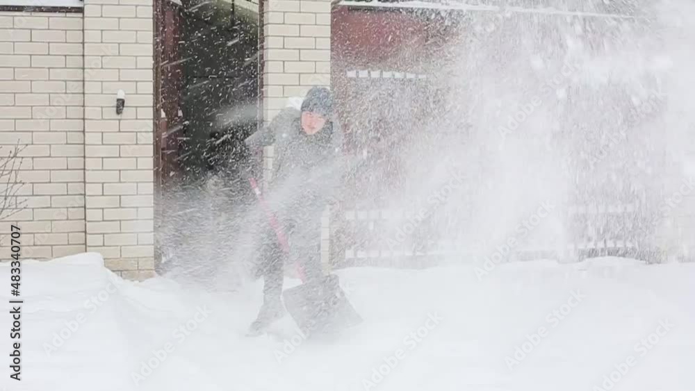 a young man cleans the snow near the house a young man cleans the snow near the house