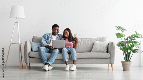 Black couple using pc and debit credit card at home