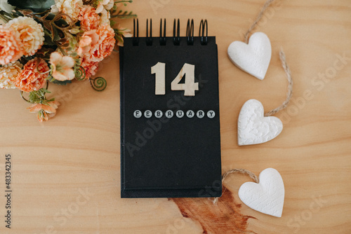 Wooden calendar on February 14 with roses and heart.