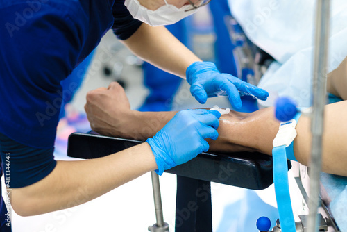 The doctor injects a catheter needle into a vein in the patient's arm. Selective focus. Intravenous administration of drugs.
