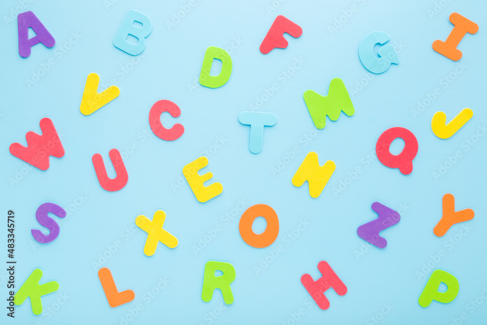 Fototapeta premium Colorful letters on light blue table. Pattern background. Pastel color. Time to learning English alphabet. Closeup. Top down view.