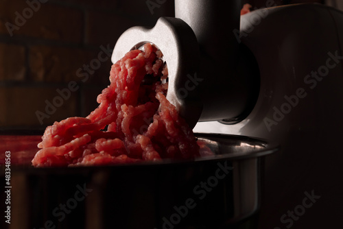 Process of preparing forcemeat by means of a meat grinder. Fresh red mincing close-up on black background with copy space. Selective focus