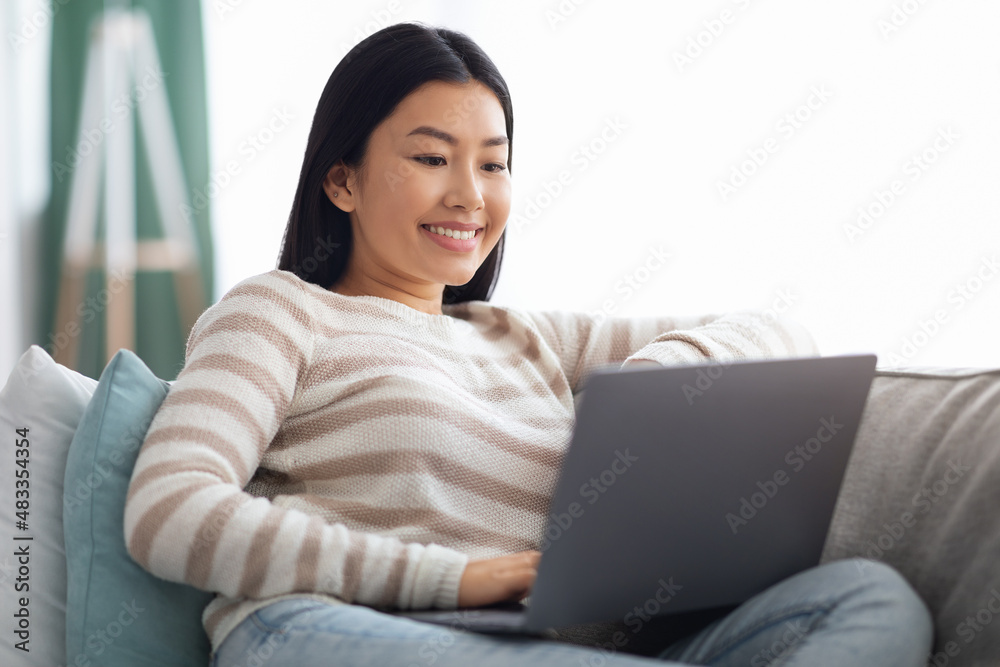 Freelance Job. Closeup Of Young Asian Woman Sitting On Couch With Laptop Freelance Job. Closeup Of Young Asian Woman Sitting On Couch With Laptop