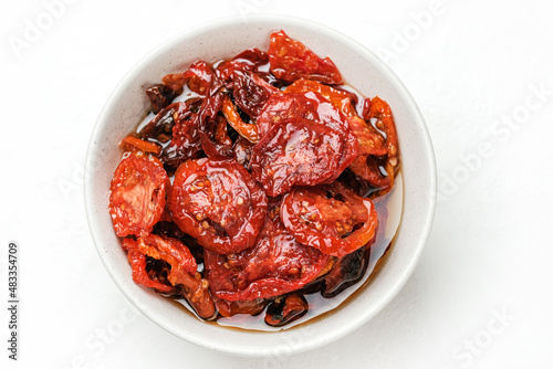 Sun dried tomatoes  on white bowl, white wooden background. Dried tomatoes  recipe.  Top view,  copyspace.