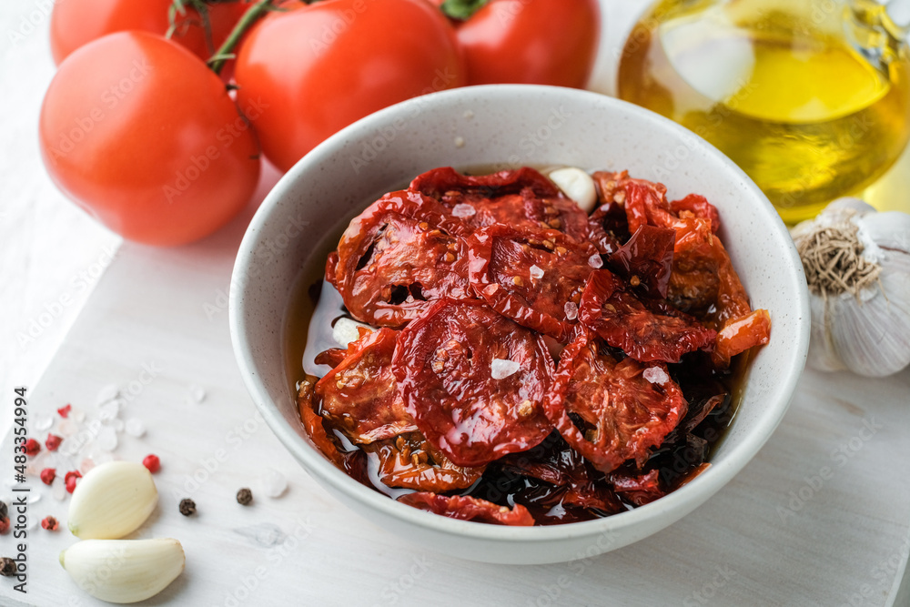 Sun dried tomatoes on white bowl, white wooden background. Dried tomatoes with olive oil, salt, herbs and garlic recipe. Top view, copyspace. Sun dried tomatoes on white bowl, white wooden background. Dried tomatoes with olive oil, salt, herbs and garlic recipe. Top view, copyspace.