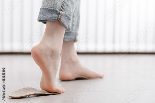 Woman fitting orthopedic insole indoors, close up. Girl holding an insole next to foot at home. Orthopedic insoles. Foot care banner. Flat Feet Correction. Treatment and prevention of foot diseases.