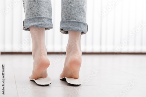 Woman fitting orthopedic insole indoors, close up. Girl holding an insole next to foot at home. Orthopedic insoles. Foot care banner. Flat Feet Correction. Treatment and prevention of foot diseases.