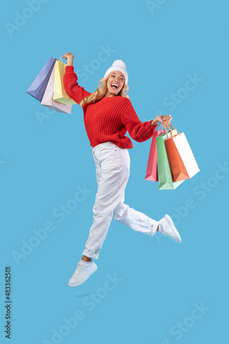 Excited woman jumping with shopping bags at studio