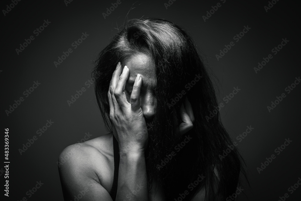 Depression or domestic violence concept: Unhappy young woman hiding her face with one hand. Sadness and boredom. 8 march Women's day or women's rights concept. Dizziness or migraine problem. Depression or domestic violence concept: Unhappy young woman hiding her face with one hand. Sadness and boredom. 8 march Women's day or women's rights concept. Dizziness or migraine problem.