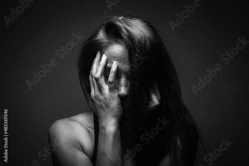 Depression or domestic violence concept: Unhappy young woman hiding her face with one hand. Sadness and boredom. 8 march Women's day or women's rights concept. Dizziness or migraine problem.