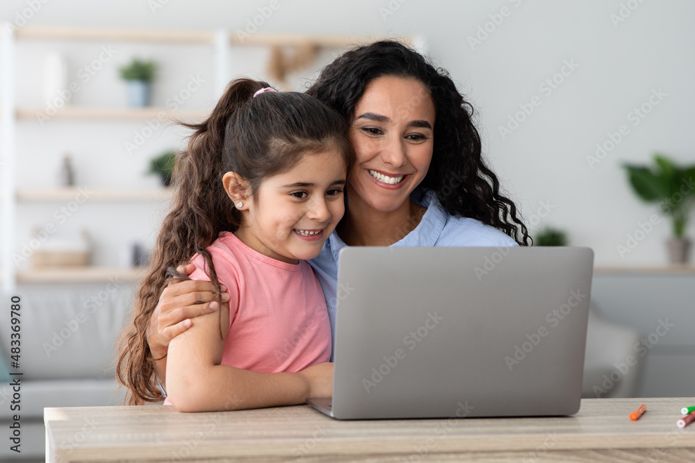 Happy Arab Mom And Little Daughter Using Laptop At Home Together Happy Arab Mom And Little Daughter Using Laptop At Home Together