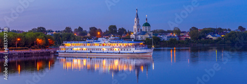 View to St. Catherine monastery with cruise ship on Volga river in summer evening. Beautiful night Russian panoramic cityscape with cruise liner on water. Travel blog concept, banner. Tver, Russia