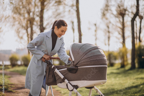 Young asian woman mother, walking with baby stroller in park