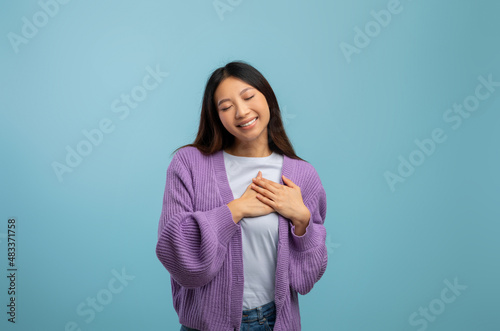 Gratitude concept. Thankful asian lady keeping both hands on chest, expressing appreciation and kindness