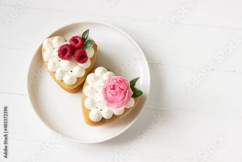 Heart shape honey cakes with fresh roses and raspberry., white plate. Valentine's day cakes, birthday, mother's day, heart shape cakes background. White background
