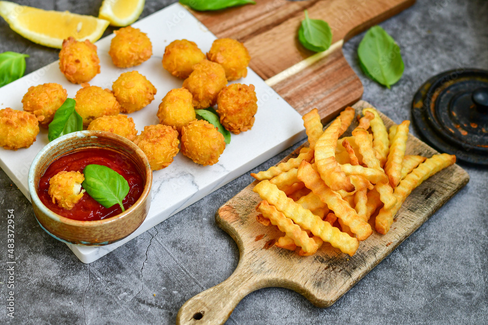 Crispy deep fried chicken popcorn nuggets and french fries . Breaded