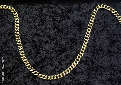 Gold jewelry. Gold chains on black leather background
