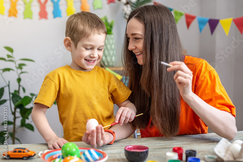 Mom and little child together are coloring eggs and having fun. Concept of family preparation for Easter, festive spring mood