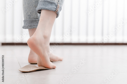 Woman fitting orthopedic insole indoors, close up. Girl holding an insole next to foot at home. Orthopedic insoles. Foot care banner. Flat Feet Correction. Treatment and prevention of foot diseases