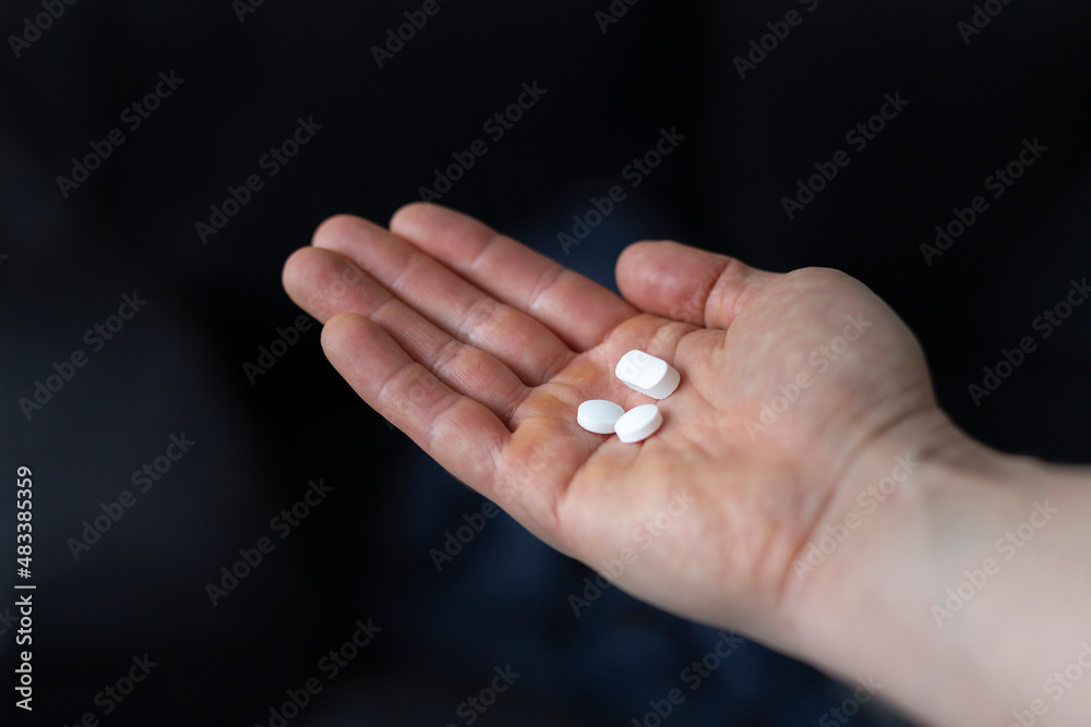 Close-up of a caucasian man holding three white medicine or vitamin pills in palm of hand. Close-up of a caucasian man holding three white medicine or vitamin pills in palm of hand.