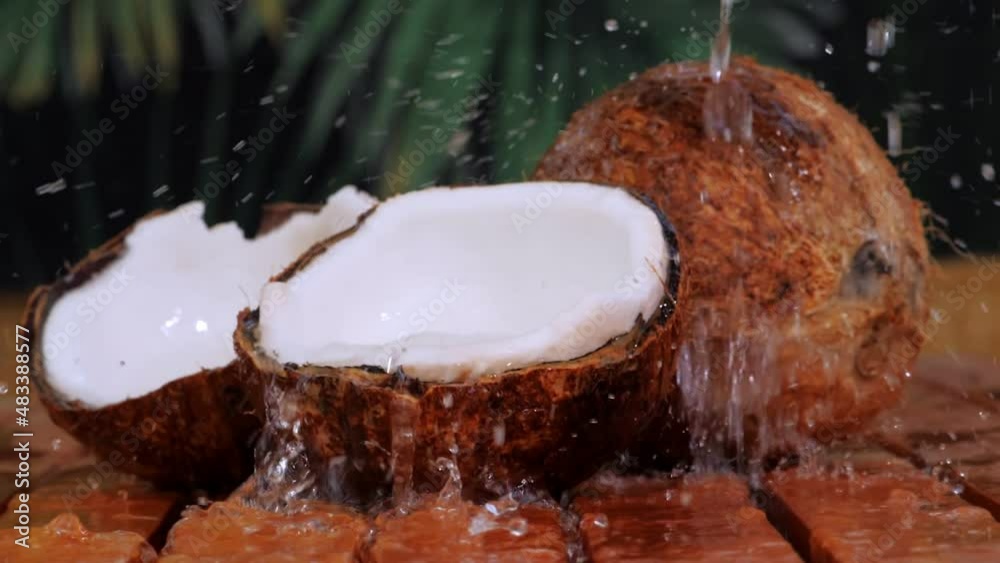 Cracked coconut with splashing water on wooden table. Cracked coconut with splashing water on wooden table.