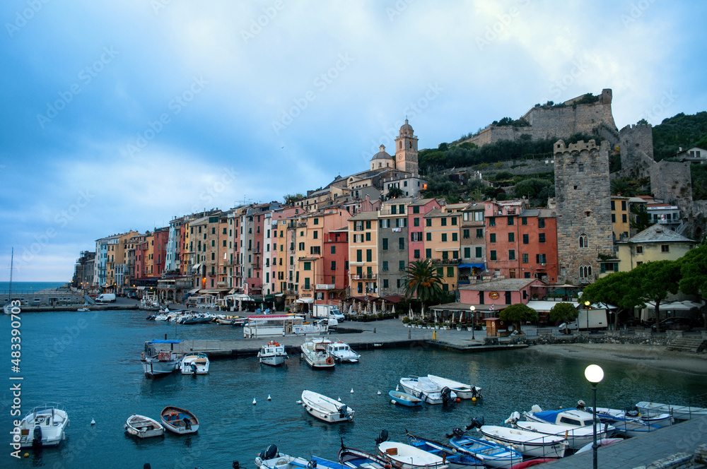 Port with small boats, waterfront and colorful houses with towers in the evening in Portovenere in the Cinque Terre (Italy).