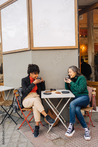 Wallpaper Mural Positive ethnic woman drinking coffee and chatting with black friend Torontodigital.ca