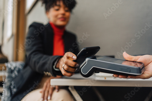 Black woman using smartphone for contactless payment in cafe photo