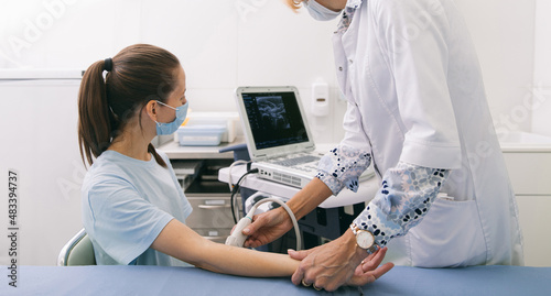 Doctor doing the ultrasound on the hand close up. Doctor demonstrates results of ultrasound to patient. Medical ultrasound scan. Rehabilitation application injection for muscle relaxation