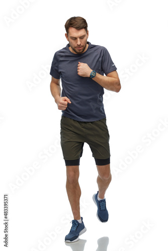 fitness, sport and healthy lifestyle concept - man in sports clothes with smart watch or tracker running over white background © Syda Productions