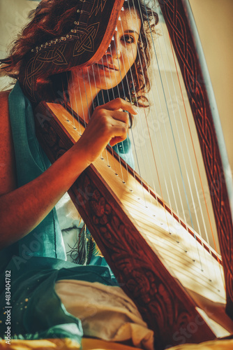 Konstfotografi Woman with a harp. Beautiful girl harpist playing her instrument.