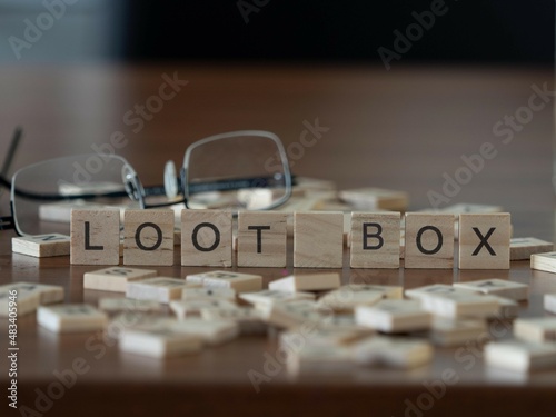 loot box word or concept represented by wooden letter tiles on a wooden table with glasses and a book photo