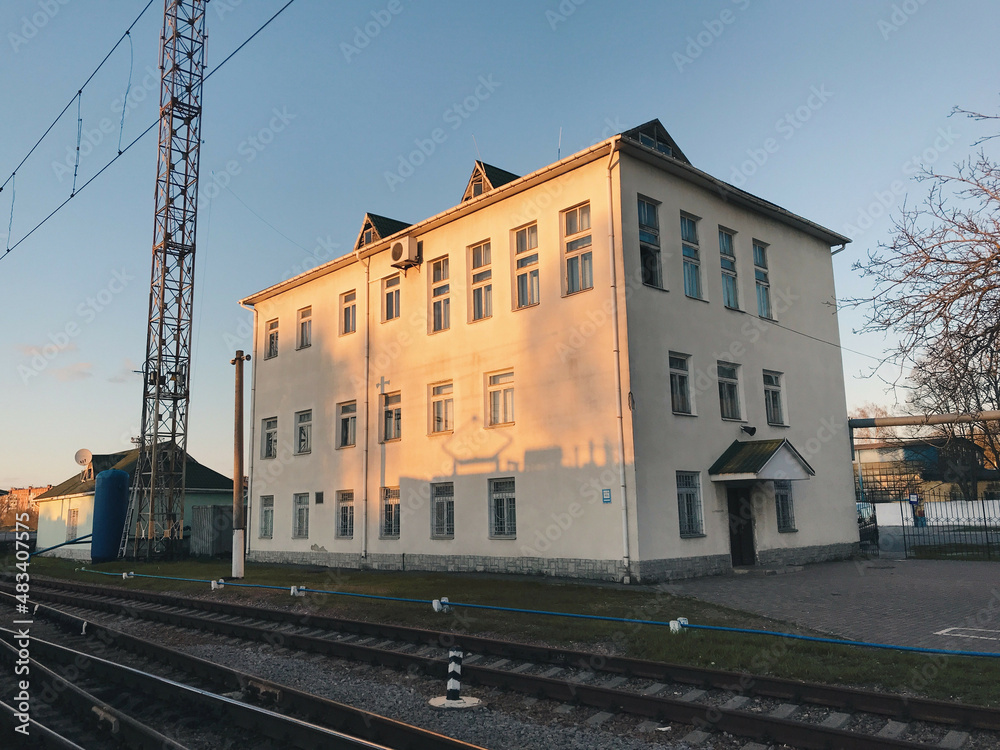Technical building at the railway station. There is a shadow from the train on the building. The picture was taken on an autumn evening. 
