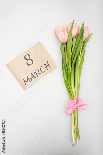top view of pink tulips with ribbon near craft paper with 8 march lettering isolated on white