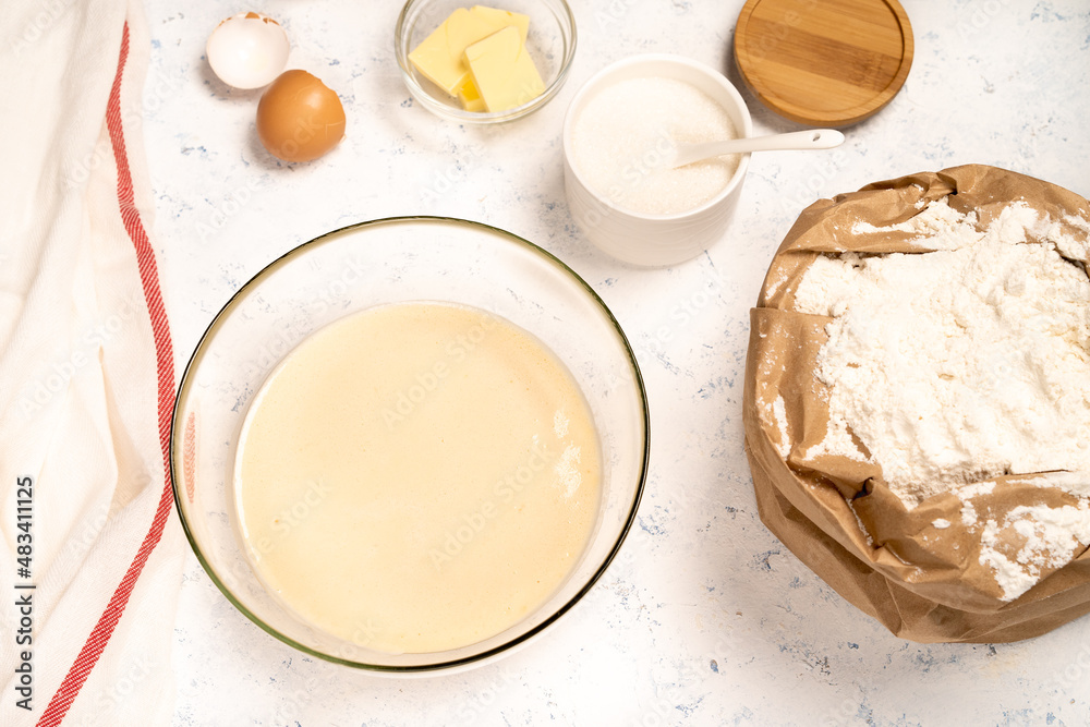 the process of making dough for pancakes with ingredients on a light table, eggs and flour are whipped with a mixer the process of making dough for pancakes with ingredients on a light table, eggs and flour are whipped with a mixer
