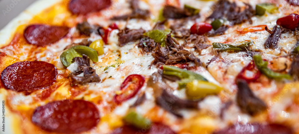Pizza with Mozzarella cheese, salami, Tomatoes, hot pepper, Spices. Italian pizza on wooden table background