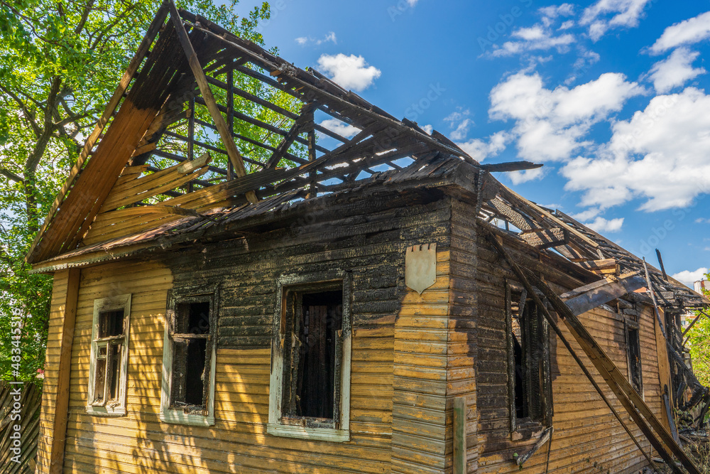 Obraz premium Burnt wooden house on city street. Abandoned destroyed residential building. Consequences of fire, tragedy. Concept of fire careless handling