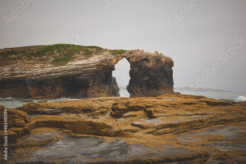 stone arch in the sea with a rock in the foreground