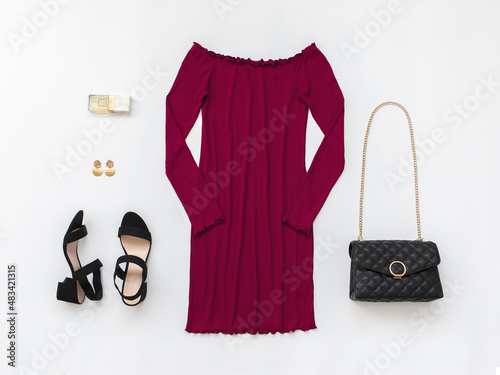 Red mini evening dress, small black bag with chain strap and heeled sandals on white background. Women's stylish outfit. Overhead view of woman's clothes. Flat lay, top view.